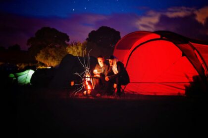 man and woman sitting beside bonfire during nigh time