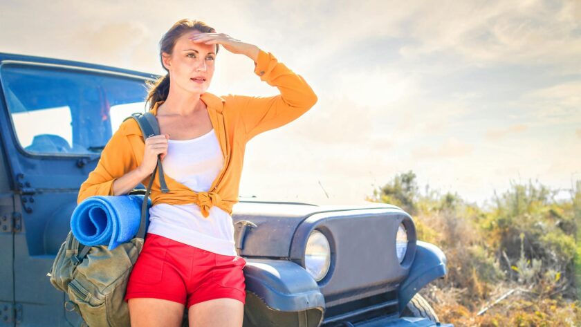 woman in yellow long sleeve leaning on blue car
