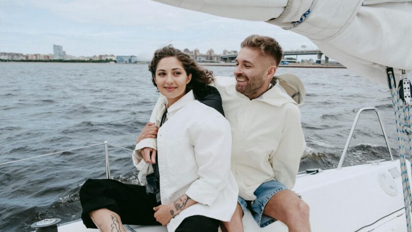 man in white suit jacket sitting beside woman in blue denim shorts on boat