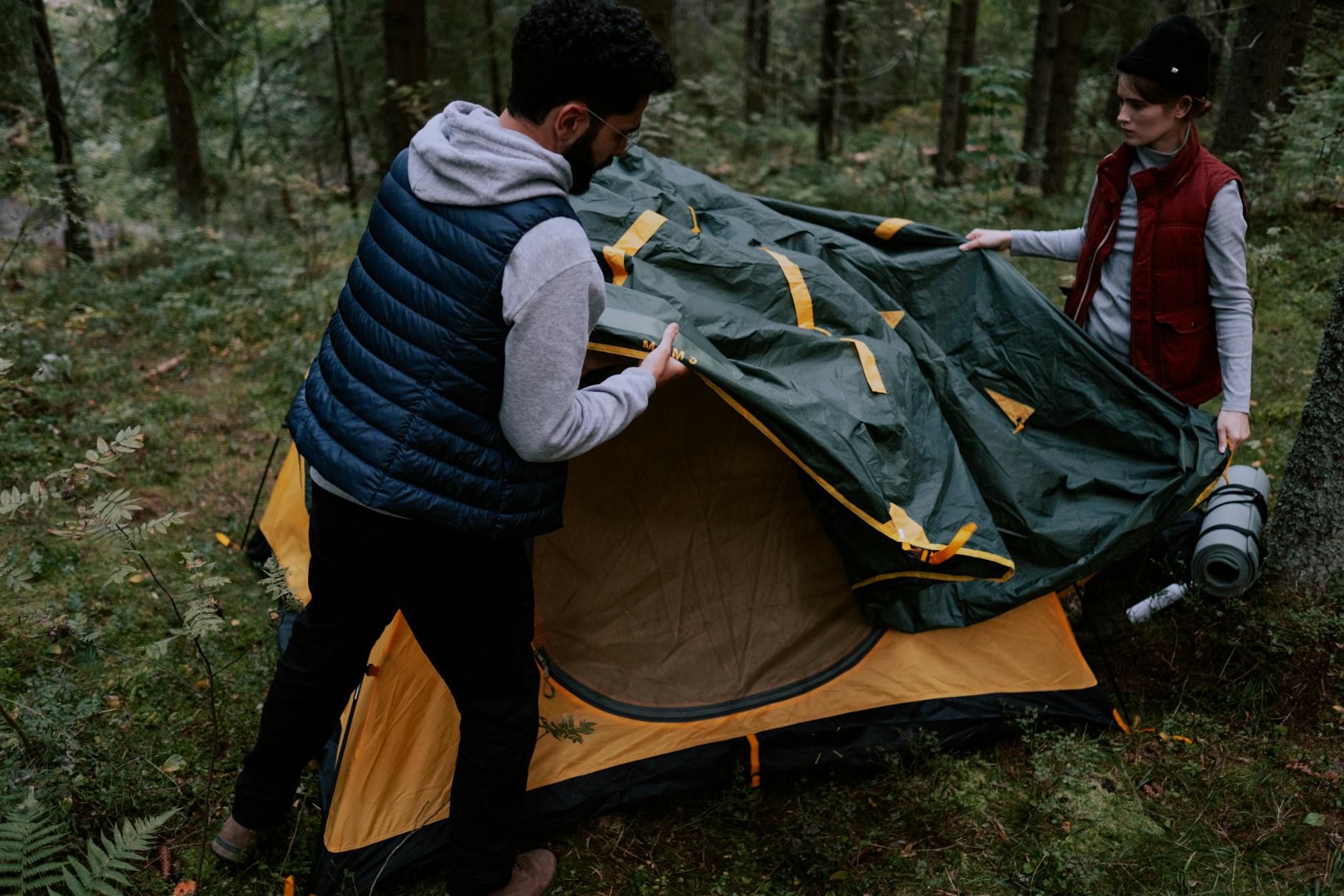 man and woman setting up a tent